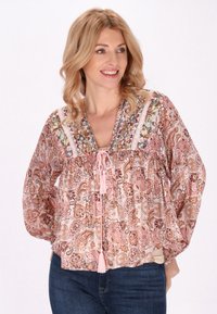 Růžová tunika s paisley vzorem a výstřihem do V, zdobená výšivkou, s tkanicí na stažení a třásněmi a dlouhými, volnými rukávy.