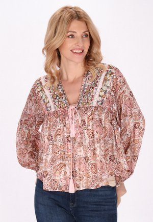 Tunic rosa con motivo paisley, scollatura a V e ricami decorativi, dotata di un laccio con pon pon e maniche lunghe e fluttuanti.