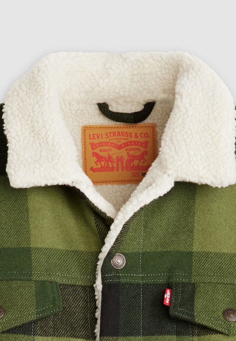 Groene geruite shirtjack met een witte sherpa-kraag. Voorzien van metalen drukknoopjes en een tanleren label aan de binnenkant. Maat M.