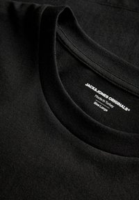 Sort bomuld t-shirt med glat tekstur, rund halsudskæring og synlig label med tekst, der angiver mærke, størrelse og oprindelsesland.