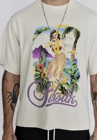 Kreemjas värvitud ülemeri t-särk, millel on elav troopiline graafika ja sõna "Siksilk" lilla värviga allosas.