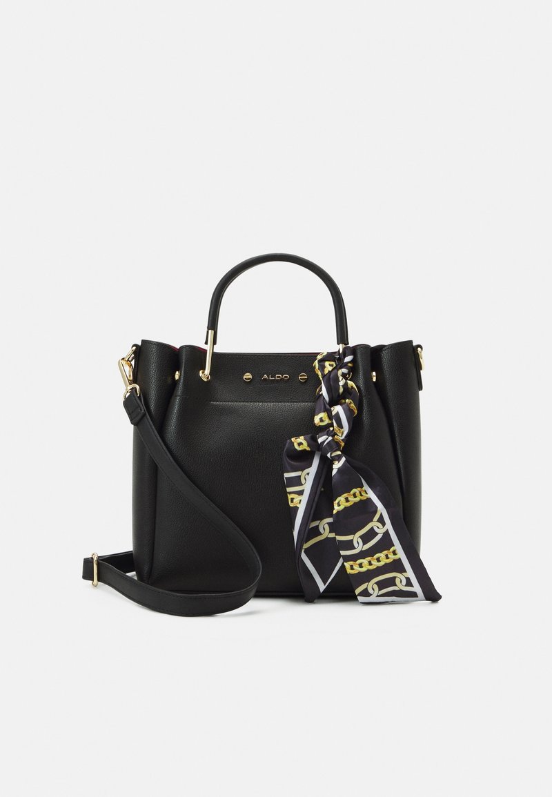 Sac à main en cuir noir avec poignée supérieure et bandoulière réglable, orné d'un foulard noir et doré à motif chaîne noué à la poignée.