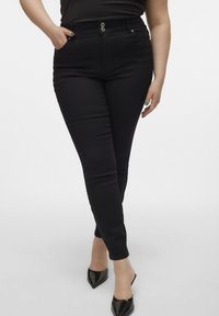 Svarta skinnyjeans i en stretchig bomullsblandning med en klassisk femfickorsdesign, metallknappstängning och slät textur.
