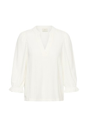 Blouse blanche à col en V, manches bouffantes et poignets à volants. Fabriquée en tissu texturé avec de petits motifs ajourés sur toute la surface.