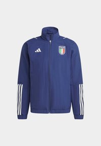 Marineblå letvægtsjakke med høj krave, fuld lynlås, tre hvide striber på ærmerne og et Italien-emblem på brystet.