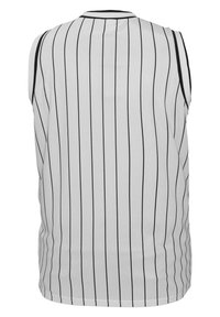 Ærmeløs hvid trøje med sorte lodrette striber, rund udskæring og ingen udsmykninger. Stoffet ser glat og let ud.