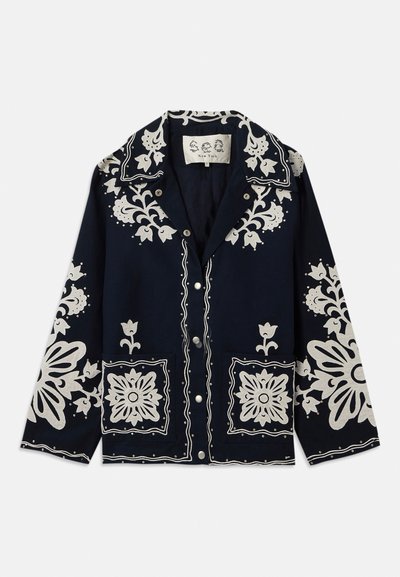 Mornarska jakna z belimi cvetličnimi izvezeninami, kvadratnimi žepi in gumbnim zapiranjem. Material se zdi teksturiran in trpežen, s klasičnim dizajnom ovratnika.