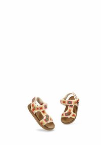 Sandalias infantiles con parte superior de tela crema que presenta bordados florales multicolores, dos correas ajustables y una suela de goma marrón.