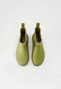 Botas de tobillo de goma verdes con una textura suave, paneles laterales elásticos y tiradores contrastantes. Presenta una etiqueta de marca en la parte delantera.