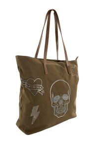 Bolsa de lona verde oliva con asas de cuero marrón. Presenta adornos de remaches plateados, incluyendo diseños de calavera, corazón, rayo y estrella.