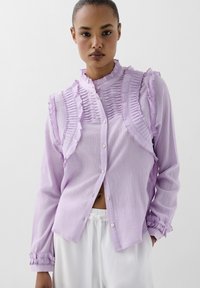 Lila blouse met ruches en knoopsluiting. Lange mouwen met gathered manchetten, gemaakt van een lichtgewicht textuurstof.