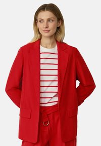 Rode blazer met een gestructureerd ontwerp, lange mouwen en twee voorzakken, gedragen over een wit en rood gestreept shirt. Gladde stoftextuur.