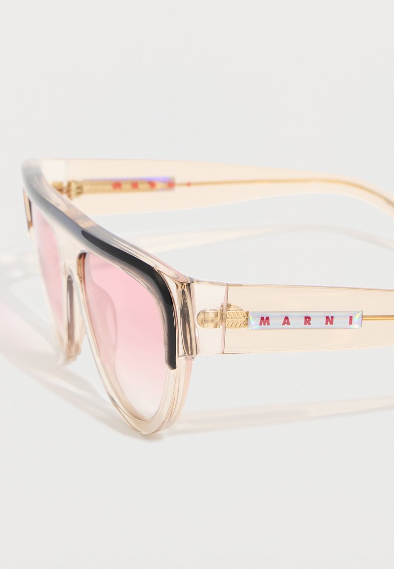 Lunettes de soleil en plastique beige transparent avec des verres à dégradé rose et un détail noir sur le bord supérieur de la monture, arborant la marque Marni sur les branches.