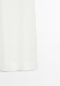 Lower section of a plain white skirt or dress against a white background, showing the hem and fabric texture.