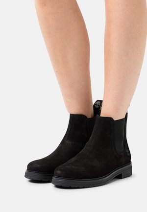 Svarta mockaankelboots med elastiska sidoskärmar, plan gummisula och sömdetaljer. Slät textur, minimalistisk design.