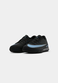 Zwarte sportschoenen met een textuur op de bovenkant, voorzien van een lichtblauwe swoosh-design en een zwarte buitenzool. Gestrikt met platte zwarte veters.