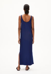 Robe longue bleu marine avec un dos plongeant, des fentes sur les côtés et un tissu doux. Le design présente de larges bretelles et une coupe décontractée.