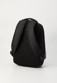 Black backpack with a textured mesh back, curved shape, adjustable straps, and a zippered compartment featuring blue hardware accents.