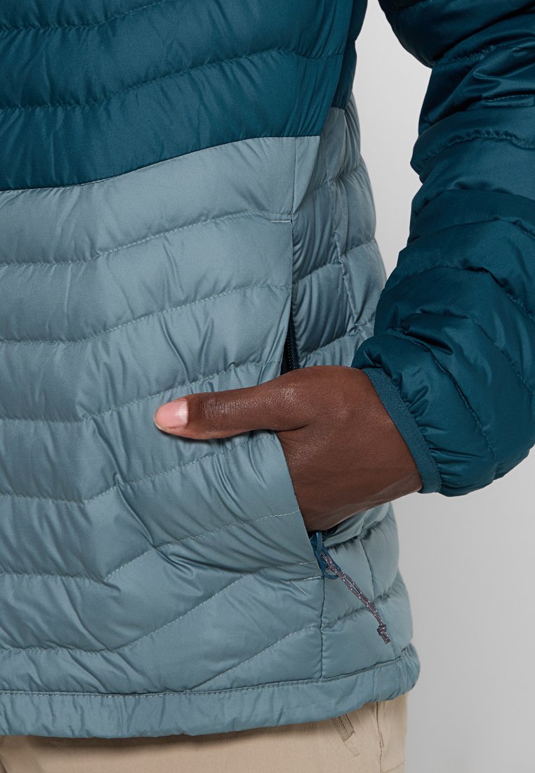 Chaqueta acolchada con un diseño bicolor en verde azulado oscuro y gris claro. Tela texturizada y acolchada con bolsillo lateral y detalle de cremallera para tirar.