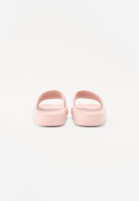 Pink slide sandals with a smooth finish, open back, textured footbed, and a slightly raised heel. Designed for comfort and casual wear.
