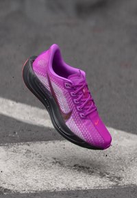 Chaussure de course Nike ZoomX avec une tige en mesh violet vif, semelle extérieure noire et accents orange contrastants sur le swoosh et la languette.