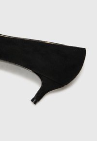 Scarpa nera in suede con tacco alto, punta affusolata e tacco sottile. Il design presenta una texture liscia e bordi senza giunture.