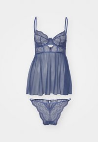 Set za perilo iz čipke in mrežaste tkanine v temno modri barvi, ki vsebuje bralette z nastavljivimi naramnicami in rahlo padajočo, prosojno babydoll bluzo. Vključuje tudi ujemajočo tangico.