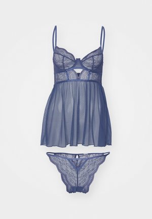 Set za perilo iz čipke in mrežaste tkanine v temno modri barvi, ki vsebuje bralette z nastavljivimi naramnicami in rahlo padajočo, prosojno babydoll bluzo. Vključuje tudi ujemajočo tangico.