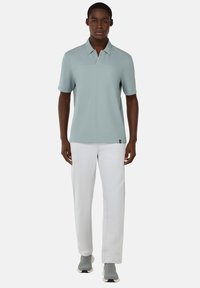 Light blue polo shirt with short sleeves and a buttoned collar, paired with white pants. Gray athletic shoes with textured accents.