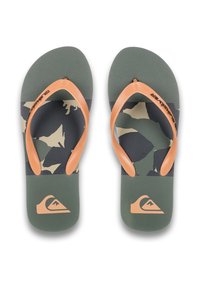 Tongs en camouflage vert et beige avec des sangles en caoutchouc orange et un semelle texturée. Logo imprimé en orange sur la semelle.