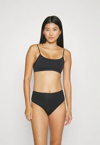 Schwarzes Bikini-Set mit einem ärmellosen Oberteil mit dünnen Trägern und hoch taillierten Hosen. Glatter Stoff mit einfachem, nahtlosem Design.