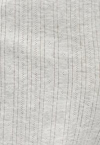 Ανοιχτό γκρι ύφασμα με κάθετες σειρές μικρών οπών που σχηματίζουν ένα διακριτικό ριγέ και κουκκιδωτό μοτίβο.