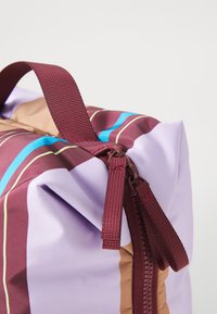 Bag with a maroon and lilac exterior, featuring blue and green stripes, a textured zipper, and a sturdy maroon handle.