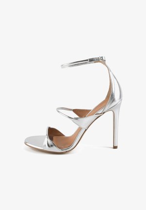 Sandal alta in argento con design a strappi, finitura metallica, punta aperta, cinturino alla caviglia regolabile e retro chiuso.