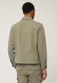 Khaki katoenen jack met een getailleerd ontwerp, knoopdetails op de mouwen en een gladde textuur. Voorzien van een klassieke kraag en een detail op de rug.