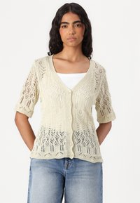Knit cardigan in light yellow with short sleeves, featuring a detailed lace pattern, V-neck, and button closure.