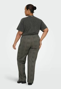 T-shirt gris foncé à manches courtes, associé à un pantalon à carreaux taille haute dans des tons terreux. Tissu lisse et coupe décontractée.