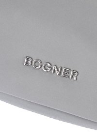 Borsa in tessuto grigio con superficie texturizzata e logo metallico argento "BOGNER". Il design è rettangolare con linee pulite e accenti minimi.