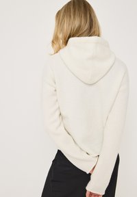 Hoodie in off-white, gemaakt van zacht materiaal. Heeft lange mouwen, een relaxte pasvorm en een achteraanzicht met een gestikte zoom.