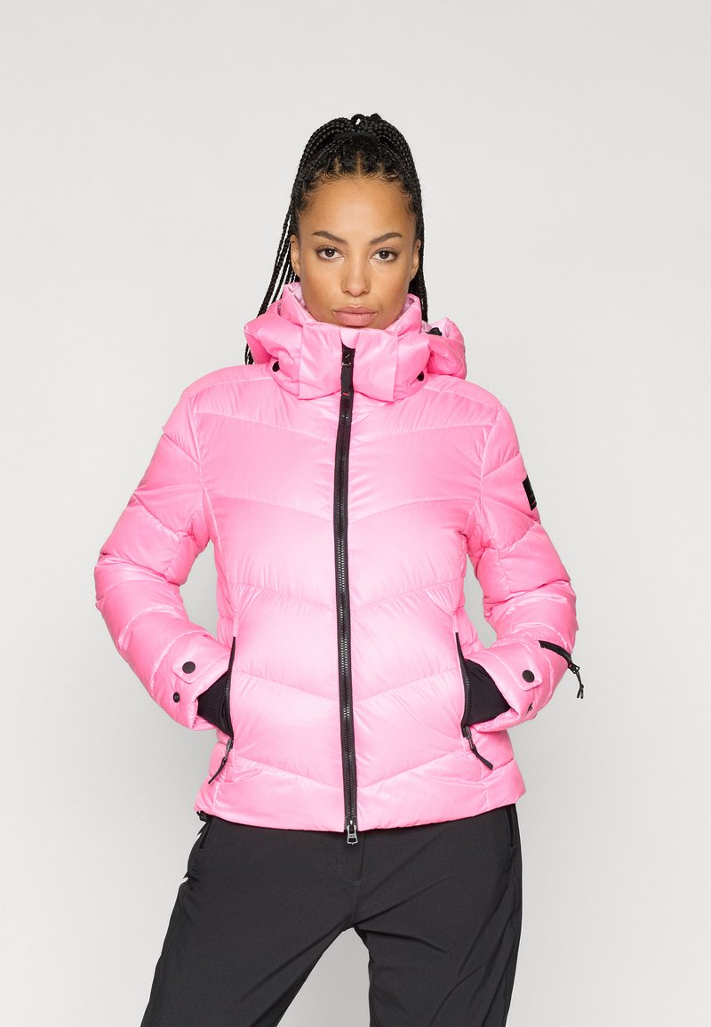 Ρόδινο φουσκωτό μπουφάν με ψηλό γιακά, μπροστινό φερμουάρ και μαύρες λεπτομέρειες. Διαθέτει ελαστικούς καρπούς και δύο πλάγιες τσέπες. Λειαντική, γυαλιστερή υφή.