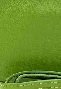 Groen leermateriaal met een gestructureerde afwerking. Bevat een bijpassende band met zichtbare stiksels en gekrulde randen.