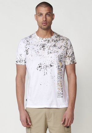 White cotton T-shirt with black and gold splatter pattern, round neckline, short sleeves, and "ENGINEERED" text printed vertically in black and gold.