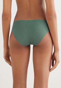 Groene, naadloze bikinionderkant met een gladde textuur, een lage taille en gematigde bedekking, met schone randen en geen zichtbare onderdelen.