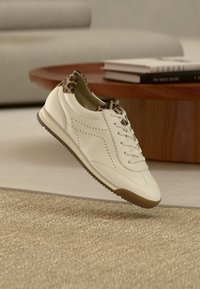 Λευκό δερμάτινο αθλητικό παπούτσι με λεπτομέρειες σε λεοπάρ τύπωμα στη φτέρνα, διατρήσεις, σχεδιασμό με κορδόνια και καφέ λαστιχένια σόλα.