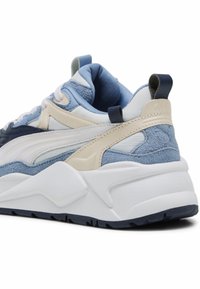 Basket chunky en blanc, beige, bleu clair et marine avec une tige en daim texturé et cuir, et une semelle épaisse blanche, vue de l'arrière.