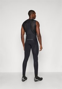 Body sportiv negru cu partea superioară din plasă texturată și secțiune inferioară netedă. Prezintă un design mulat și detalii cu logo pe spate.