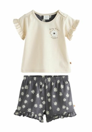 Lichtbeige korte mouw top met ruches en bloemenborduursel, gecombineerd met donkergrijze shorts met een witte madeliefjespatroon en een gerimpelde zoom.