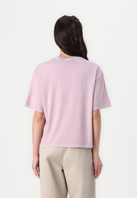Short-sleeve, lavender cotton t-shirt with a relaxed fit, crew neck, and a slightly cropped hem. Minimal stitching details.