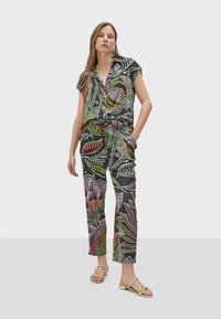 Multicolored tropical print outfit featuring a short-sleeve shirt and loose-fitting pants, both with a dark background and bold leaf designs.
