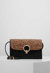 Sac à main noir tissé avec un rabat en imprimé léopard, fermeture à anneau en métal doré et une bandoulière noire amovible. Matériaux texturés sur l'ensemble.